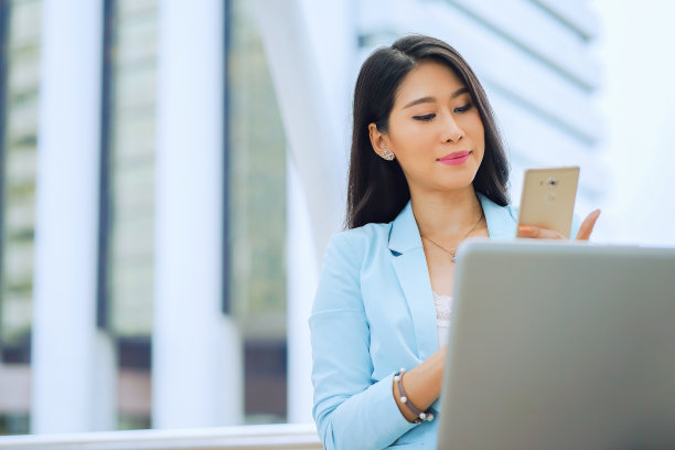 年轻的亚洲女性使用智能手机的城市背景。图片下载