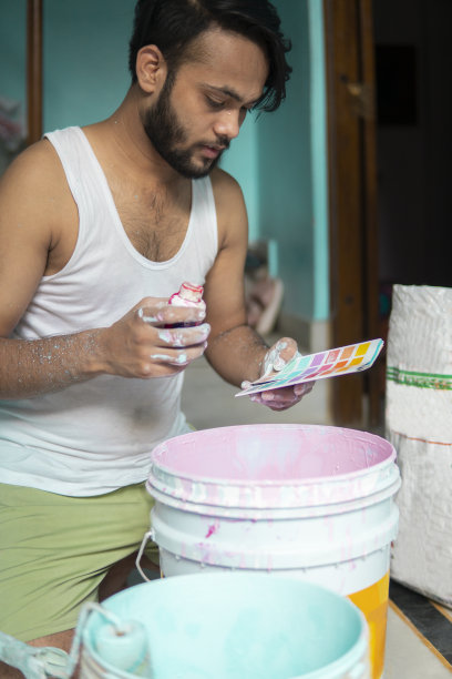 油漆工拿着色瓶调色板，为家庭装饰准备油漆。图片下载