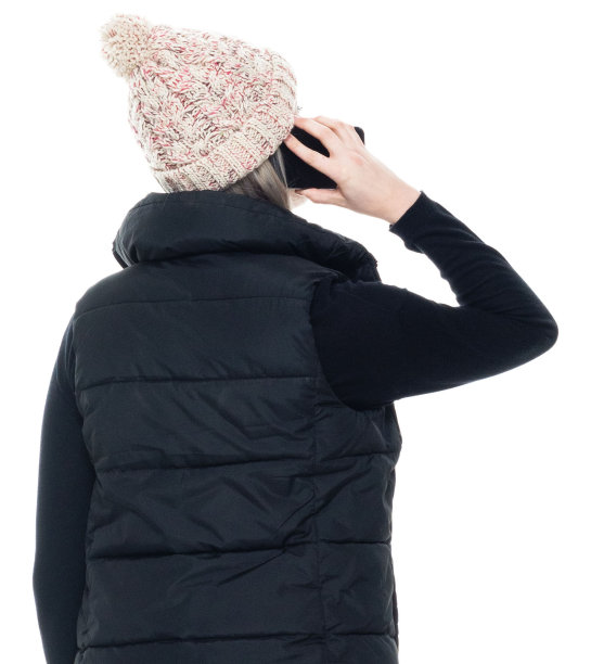 白种人的年轻女性穿着保暖的衣服，穿着无袖的衣服站在白色的背景前，用手机图片下载