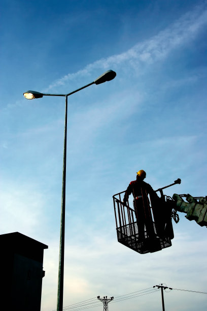 电力技术人员在高高的路灯杆上的水桶里工作图片下载
