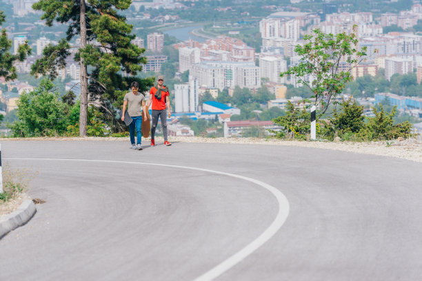 两个滑板手拿着长板，边滑边聊。图片下载