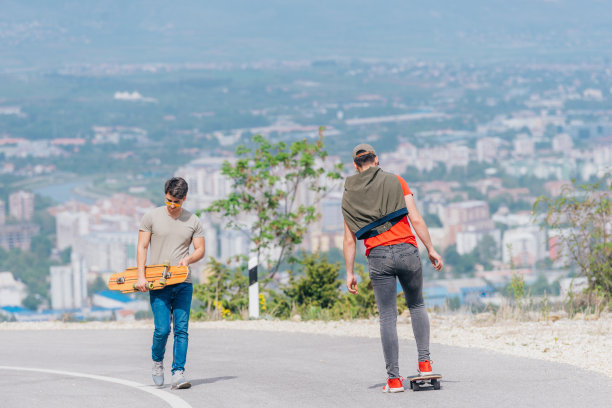 身材高大的运动员穿着红色t恤和黑色牛仔裤，快速平稳地骑着长板下坡。图片下载