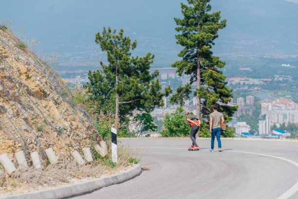 身材高大的运动员穿着红色t恤和黑色牛仔裤，快速平稳地骑着长板下坡。图片下载
