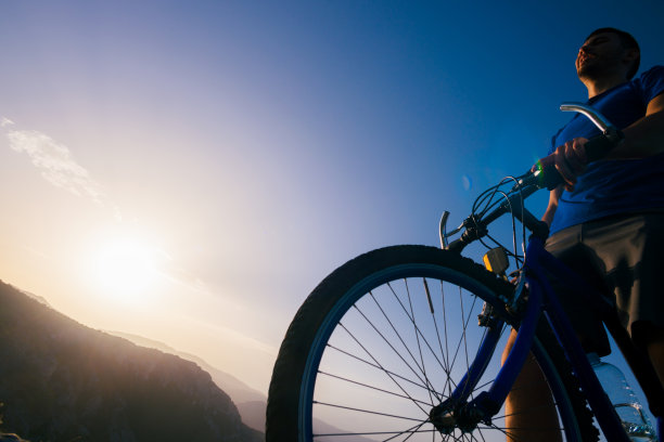 一个运动员(山地自行车手)的特写轮廓骑在岩石山上的自行车。图片下载