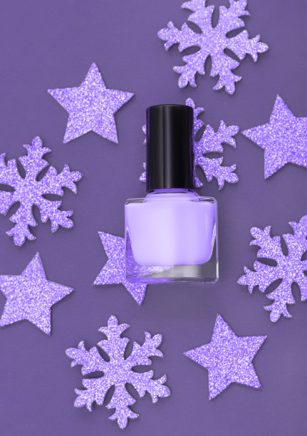 紫色的指甲油瓶子，紫色的圣诞星星和紫色背景上的雪花。美容产品的概念。指甲油瓶盖。图片下载