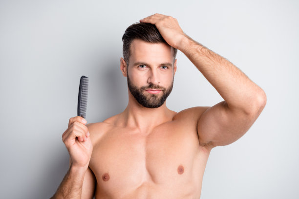 年轻英俊的男子的照片，持有发刷享受护发素洗发水孤立在灰色的背景色图片下载