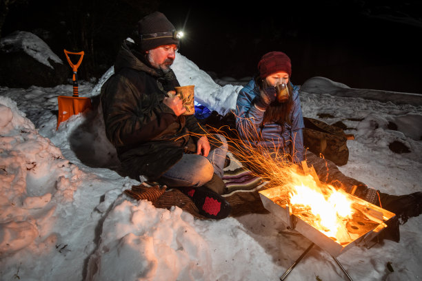 一对夫妇在他们的雪营地放松，享受饮料图片下载