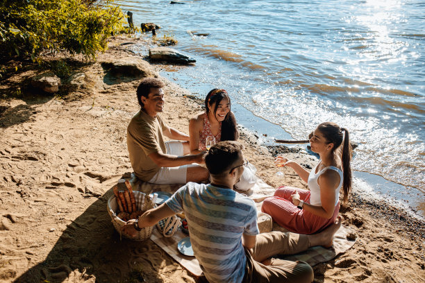 各式各样的朋友在河边野餐。图片下载