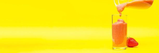 草莓奶昔，黄色背景的烹饪过程，自制奶昔，玻璃奶昔图片下载