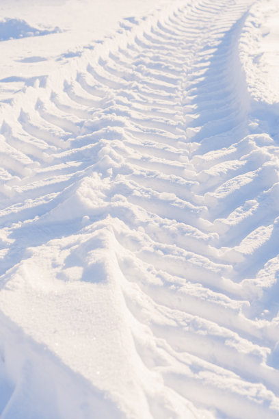 雪地上拖拉机车轮的痕迹。清除积雪时市政服务设备的踏面印记。垂直与图片下载