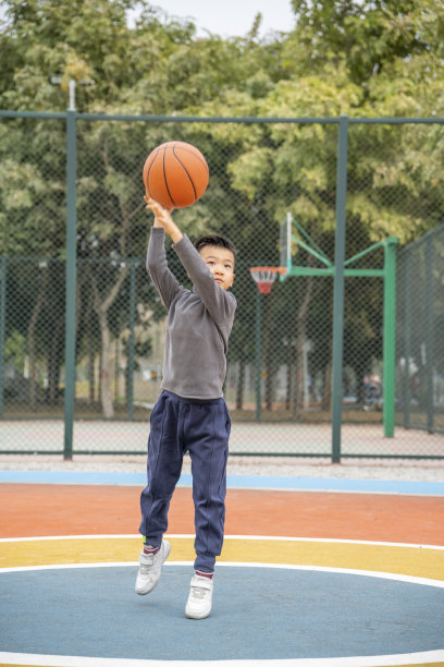 一个小男孩在学校操场上打篮球图片下载