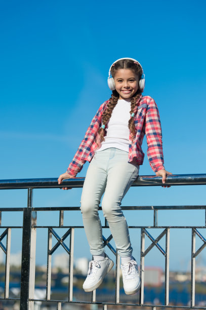 喜欢的声音。让你的孩子开心，最好的儿童耳机，现在就可以使用。小女孩带着现代耳机在户外听音乐。孩子们测试了耳机，结果从最好到最差图片下载