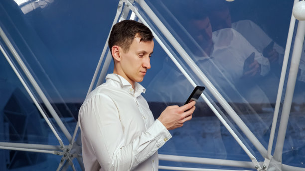 男子靠在大玻璃窗上通过手机查看社交媒体图片下载