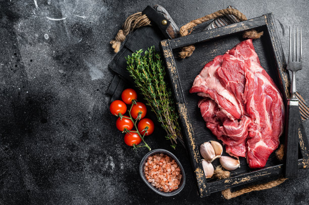 羔羊颈肉或羊肉颈肉，生的无骨肉在木制托盘。黑色背景。前视图。本空间图片下载