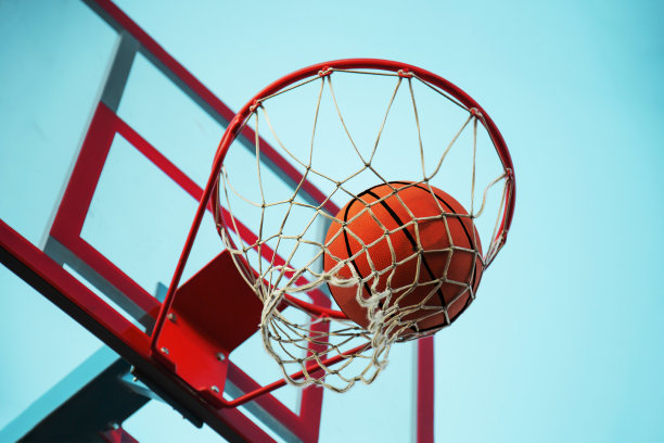 一个篮球在网里。飞球在篮筐里。一个体育游戏。图片下载