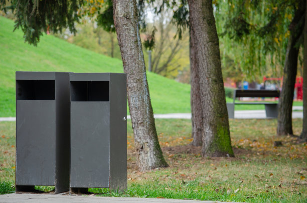 公园里有两个铁垃圾桶，背景是树木图片下载