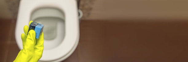 手里拿着马桶方块清洁剂。一只手将一个消毒方块放入安装在墙上的抽水马桶的水中图片下载