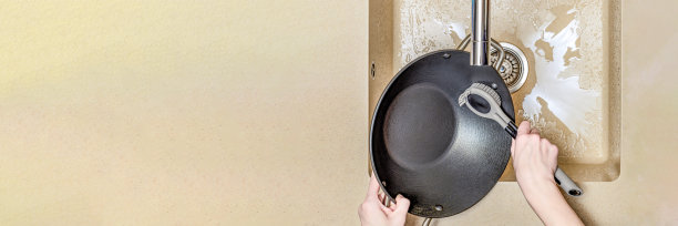 一个女人在洗煎锅，一只手在厨房水槽里洗煎锅，一个女人在用硅胶刷洗盘子。文本的地方图片下载