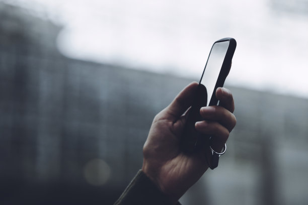 男性手使用智能手机，背景自然模糊图片下载