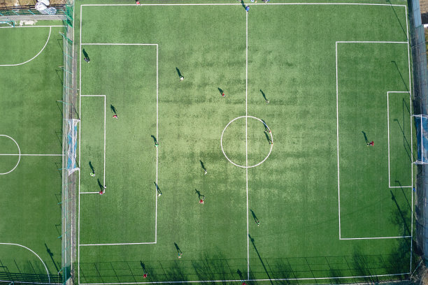 足球运动员在绿色的体育场踢足球的鸟瞰图。图片下载