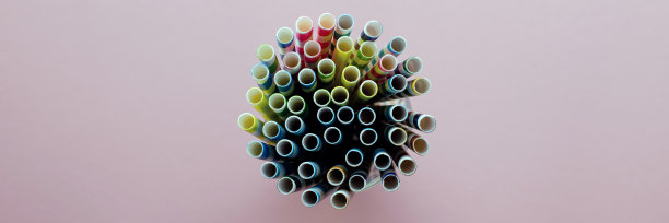 饮用吸管。彩色纸鸡尾酒管在粉红色的背景。在一个玻璃杯里。从顶部看，特写图片下载