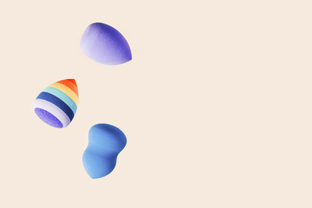 化妆海绵是蓝色和亮条纹的。柔软化妆海绵美容搅拌器，脸部化妆刷，面部涂抹器。背景为沙龙时尚美容化妆。关闭泡芙图片下载