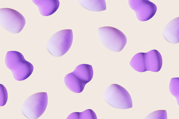 图案与化妆海绵紫色，紫色。柔软的化妆海绵美容搅拌器，面部化妆刷，面部涂抹器。背景为沙龙时尚美容化妆。图片下载