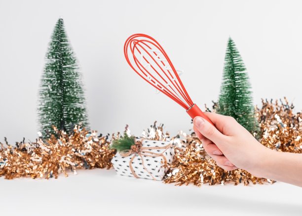 手上拿着红色的搅拌工具，背景是圣诞和新年装饰图片下载