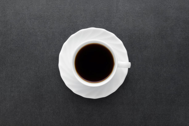 白色杯子的新鲜黑咖啡在黑色的桌子背景。特写镜头。自顶向下的观点。图片下载