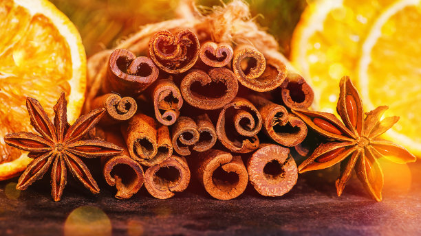 肉桂棒，八角茴香，干柠檬，用于准备秋冬暖饮，背景是一棵花环和散景圣诞树。烹饪食材，圣诞装饰。图片下载