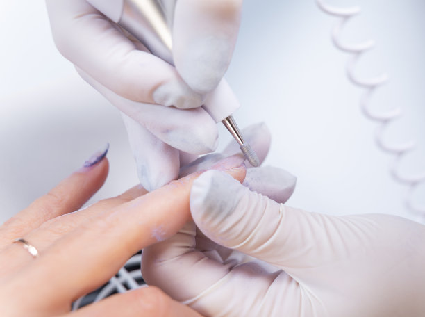 用电子锉刀治疗指甲的特写照片。美甲师用指甲钻去除指甲上的凝胶指甲油。图片下载