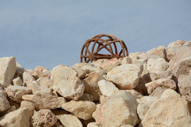 照片：地中海沿岸建筑工地上的一大堆石头，天气平静图片下载
