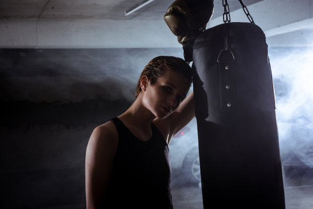 女拳击手的剪影照片，她的头靠在拳击皮袋上图片下载
