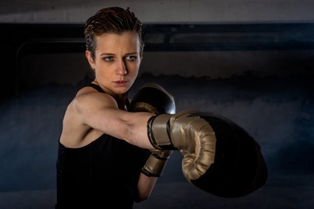 特写照片美丽的女拳击手练习她的拳头与金拳击手套图片下载