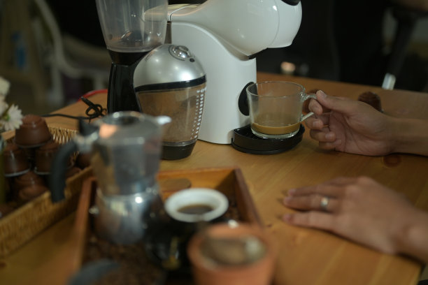 在被咖啡设备包围的咖啡吧里，一只手在用咖啡机煮咖啡。图片下载