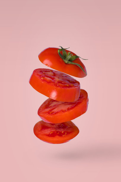 切成薄片的番茄在空中飞舞，孤立在亮粉色的背景上。生素食健康饮食配料。图片下载