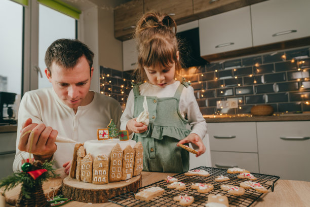 父亲和女儿在厨房装饰姜饼蛋糕图片下载