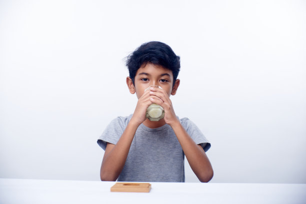 一个亚洲男孩拿着一杯健康的新鲜牛奶图片下载