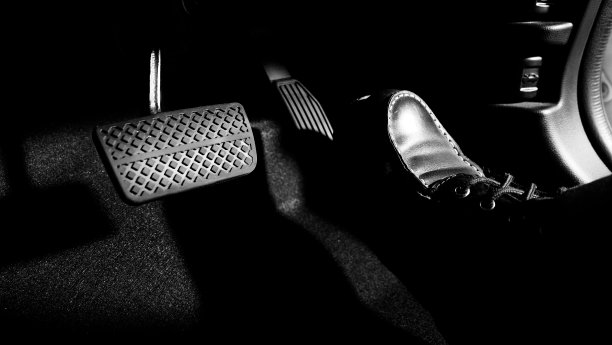 汽车的油门和刹车踏板。紧踩汽车的脚踏板向前行驶。司机通过推动汽车的油门踏板来驾驶汽车。脚踏板在车内。图片下载