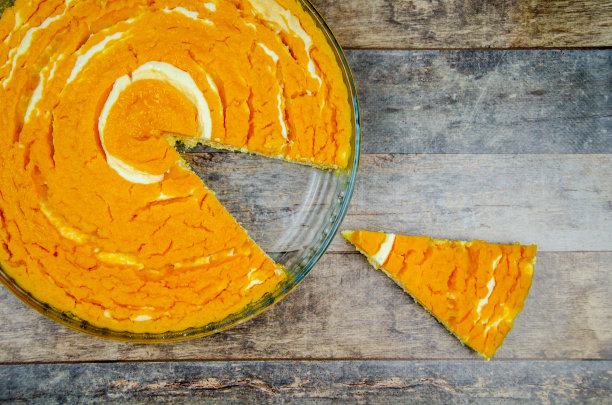南瓜豆腐砂锅。南瓜芝士蛋糕片旁边的大浅盘派在木制背景图片下载