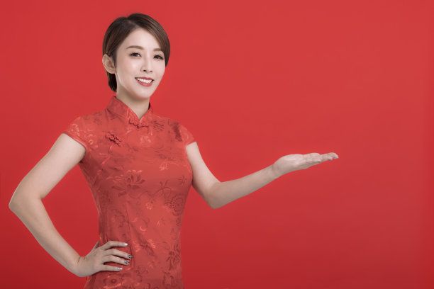 春节快乐。亚洲妇女穿着传统旗袍，用手势进行介绍素材图片
