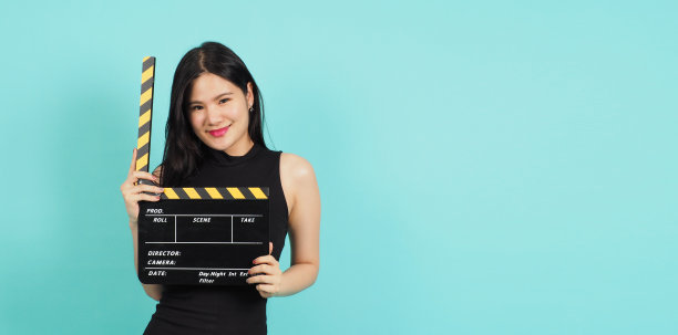 拍板或电影拍板，少女或妇女的手，黑色和黄色。它用于视频制作，电影，电影行业的绿色或蒂芙尼蓝色背景。她穿着黑色的连衣裙图片下载