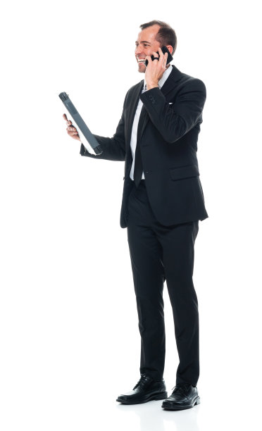 白种年轻男性，穿着职业装，手持文件，使用手机，站在白色背景前图片下载