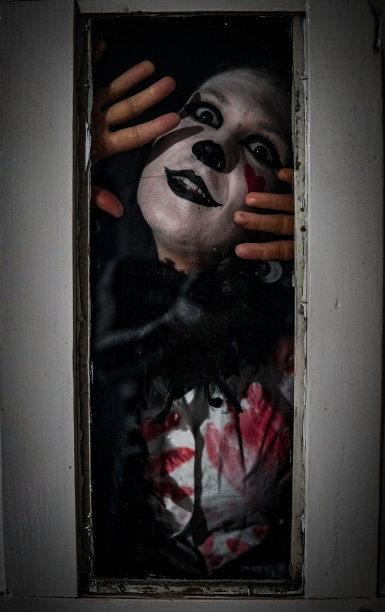 一个穿着哑剧服装的女性在玻璃后面摆姿势的垂直恐怖镜头图片下载