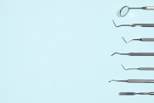 一些医疗牙科工具和镜子在浅蓝色背景与复制空间。平躺接近顶部视图与牙科设备。牙齿保健，口腔卫生保健理念。图片下载