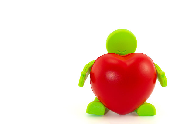 抱着一颗心的坐着的玩具人。献出你的爱和情人节假期图片下载