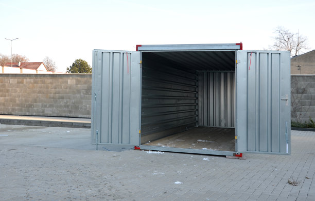 院子里有一个大容量的集装箱，地板是木地板。作为车库，工具仓库，或临时住所转换成一个住宅单元。打开金属门图片下载