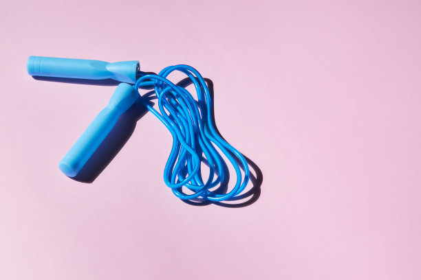 蓝色跳绳或跳绳在粉红色的背景。图片下载