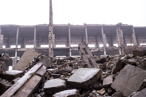 在一片朦胧中，一堆巨大的混凝土碎片映衬着被摧毁的建筑框架。背景图片下载