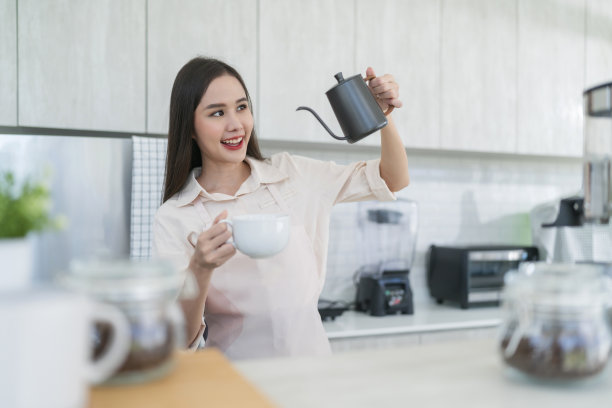 幸福快乐的亚洲女性在制服小店咖啡馆的老板在咖啡馆工作，中国女咖啡师用咖啡机在咖啡馆倒牛奶图片下载